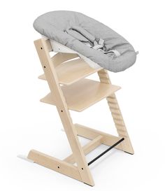 a wooden high chair with a grey blanket on the top and seat pad in front of it