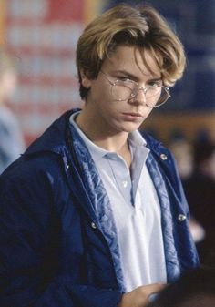 a young man wearing glasses and a blue jacket