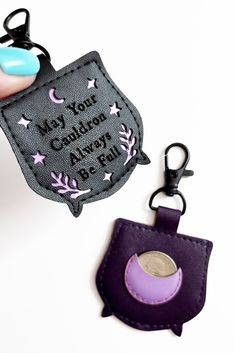 a hand holding a purple and black keychain with a tag attached to it