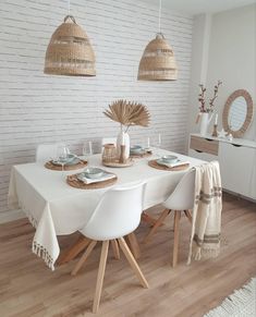 a dining room table with white chairs and wicker baskets hanging from the ceiling over it