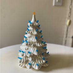 a ceramic christmas tree with blue and white decorations on it's base, sitting on a table