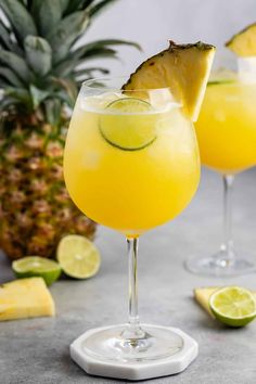 two glasses filled with pineapple margaritas and garnished with sliced pineapple