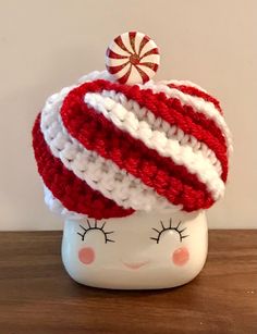 a red, white and blue crocheted hat with candy cane on top sitting on a table