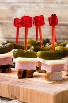 pickles and ham are arranged on a cutting board with toothpicks sticking out of them