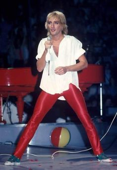 a man in red pants holding a microphone