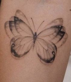 a black and white butterfly tattoo on the arm