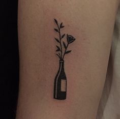 a black and white photo of a bottle with a flower in it on the arm