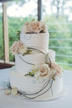 a three tiered cake with flowers on the top and bottom is sitting on a table