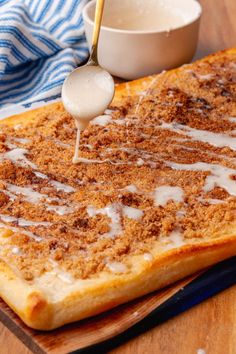 a person dipping something into a bowl on top of a piece of bread with icing