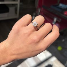 a person's hand holding a ring with a diamond in the middle and on top of it