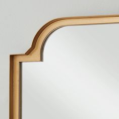 an arched mirror is hanging on the wall next to a white wall and wooden frame