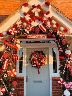 christmas wreaths and candy cane decorations decorate the front door of a home in red, white and green