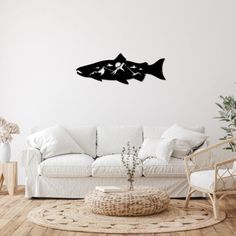 a living room with a white couch and black fish wall decal on the wall