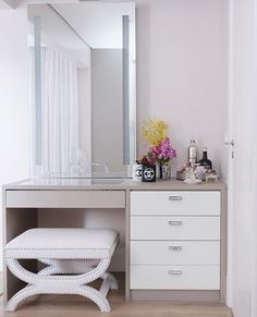 a white vanity with drawers and a stool in front of it, next to a mirror