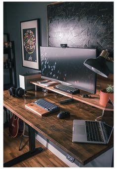 a desk with a laptop, keyboard and mouse on it in front of a wall mounted monitor