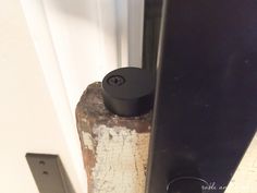 a black speaker sitting on top of a piece of wood in front of a door