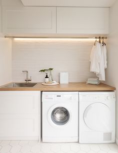 a washer and dryer in a small room with white tile flooring on the walls