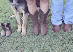 two people standing next to a dog wearing cowboy boots