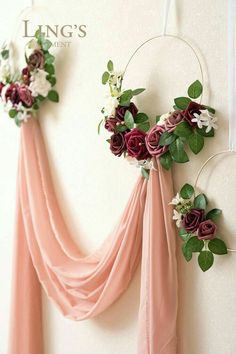 two flowers are hanging on the wall next to some draping and greenery