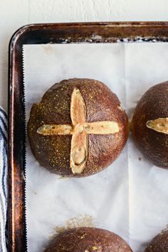 four baked breads on a baking sheet with one cut in half and the other whole