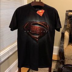 a black superman t - shirt hanging on a chair