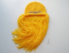 a crocheted yellow hat with long hair on it's side and a diamond in the middle