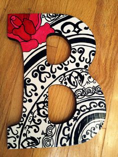 the letter b is made out of wood and has a red rose on it's side