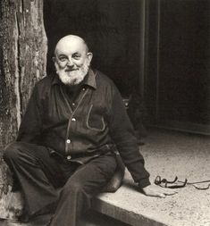 an old man sitting on the steps next to a tree with his feet propped up