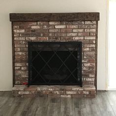 an empty room with a brick fireplace and wood floors