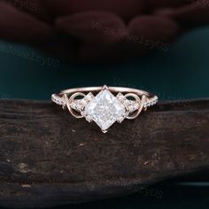 an engagement ring with three stones on top and two diamonds in the middle, sitting on a tree branch