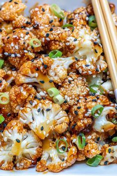 a plate full of cauliflower with chopsticks on the side and sesame seeds