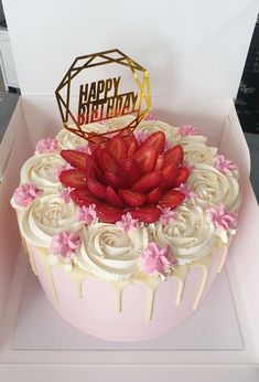 a birthday cake with white frosting and strawberries on top in a pink box