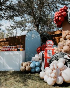 an assortment of balloons and decorations on display in front of a wooden fence with trees