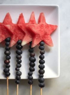 watermelon and blueberries are arranged on skewers