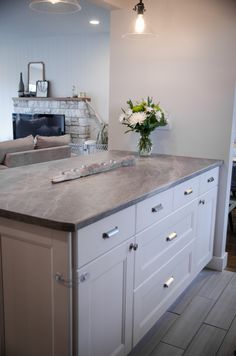 a kitchen island with flowers on it in front of a fireplace and couch behind it