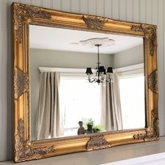 a large gold framed mirror hanging on the wall