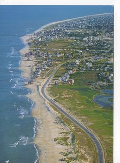 an aerial view of a beach and the ocean with houses on it's sides