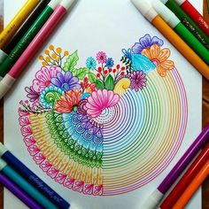 colored pencils and markers are sitting on a paper with an image of flowers in the center