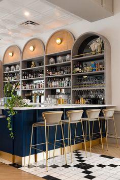 an empty bar with stools and bottles on the shelves