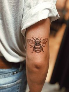 a woman with a bee tattoo on her arm