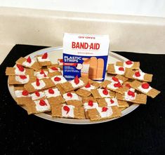 a white plate topped with crackers and marshmallows next to a box of band aid