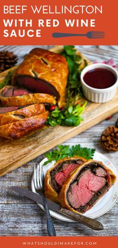 beef wellington with red wine sauce on a cutting board next to some bread and garnish