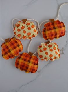 four pumpkins hanging from strings on a marble surface