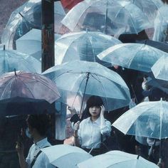 a group of people standing around each other holding umbrellas