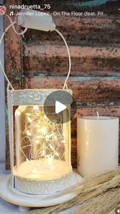 a white lantern with fairy lights inside on a table next to a broom and candle