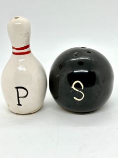 two bowling pins and a bowling ball sitting next to each other on a white surface