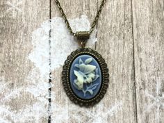 Beautiful brass necklace with a blue flower and butterfly cameo pendant, Selma Dreams Antique Flower Pendant Necklace For Gift, Antique Flower Pendant Necklace As Gift, Vintage Charm Oval Pendant Necklace As Gift, Oval Pendant Necklace With Vintage Charm For Jewelry Making, Victorian Style Necklace With Large Pendant As Gift, Costume Jewelry Locket Necklace For Gift, Oval Costume Jewelry Necklace For Gift, Bohemian Cameo Jewelry For Gifts, Vintage Charm Oval Necklaces For Jewelry Making