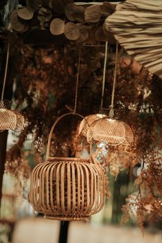 two wicker lamps hanging from the ceiling in front of an umbrella and some trees