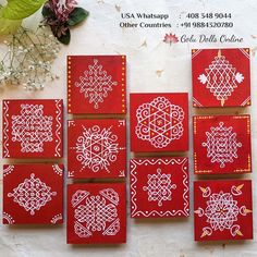 six red coasters with white designs on them sitting next to a flower vase and some flowers