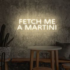 a neon sign that reads fetch me a martini on the wall above a table and chairs